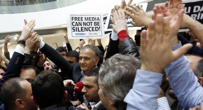 Zaman editor-in-chief Ekrem Dumanli (C), escorted by plainclothes police officers, is cheered by his colleagues as he leaves the headquarters of Zaman daily newspaper in Istanbul, Dec. 14, 2014. (photo by REUTERS/Murad Sezer)