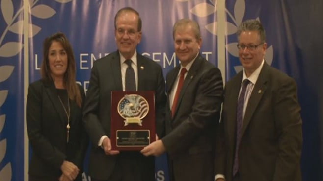 Sheriff Edward V. Rochford accepts a plaque from Peace Islands Institute Director Ercan Tozan