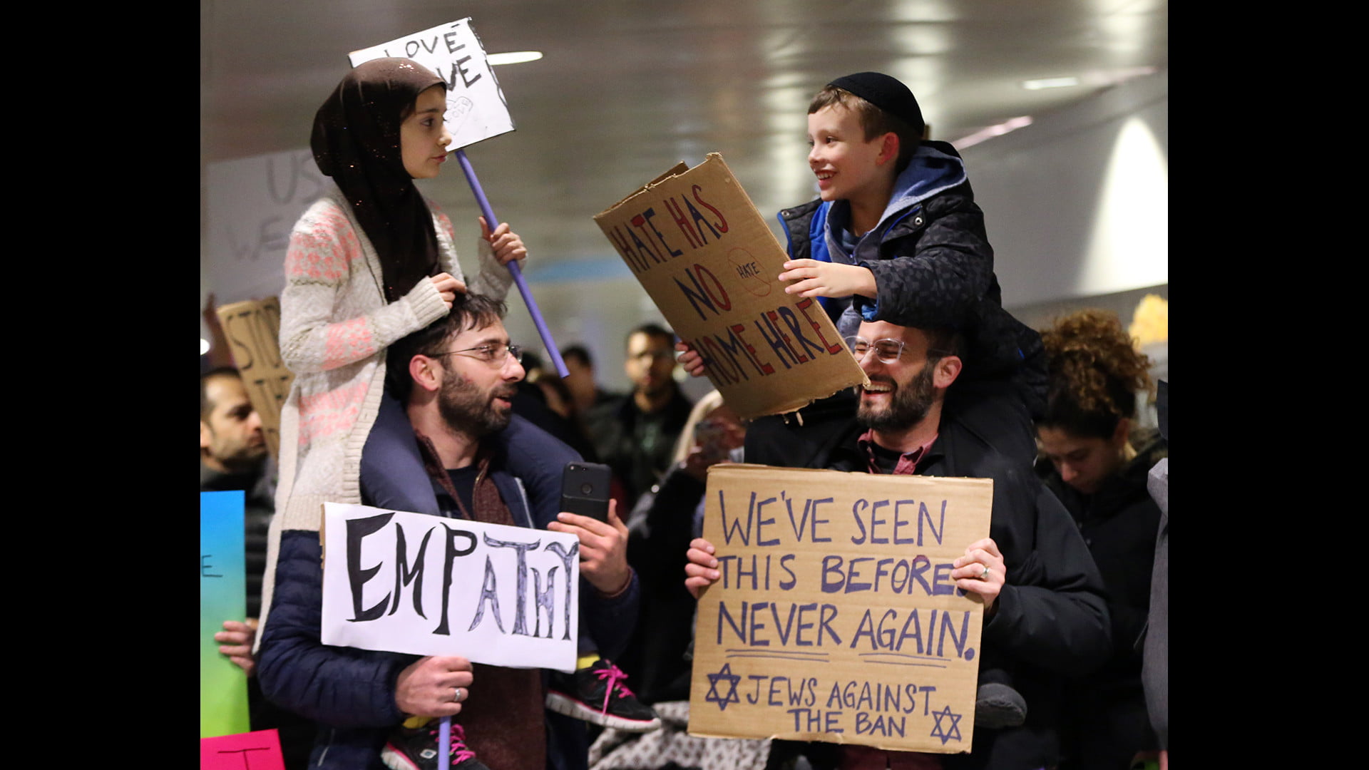 Meryem Yildirim, 7, left, sitting on the shoulders of her father, Fatih, of Schaumburg, and Adin Bendat-Appell, 9, sitting on the shoulders of his father, Rabbi Jordan Bendat-Apell, of Deerfield, protest President Donald Trump's immigration and refugee order at O'Hare International Airport on Jan 30, 2017. (Nuccio DiNuzzo / Chicago Tribune)