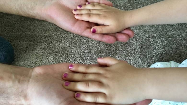 Father and daughter hold hands on Friday in Edmonton after fleeing Turkey and spending nearly two years apart. (CBC)